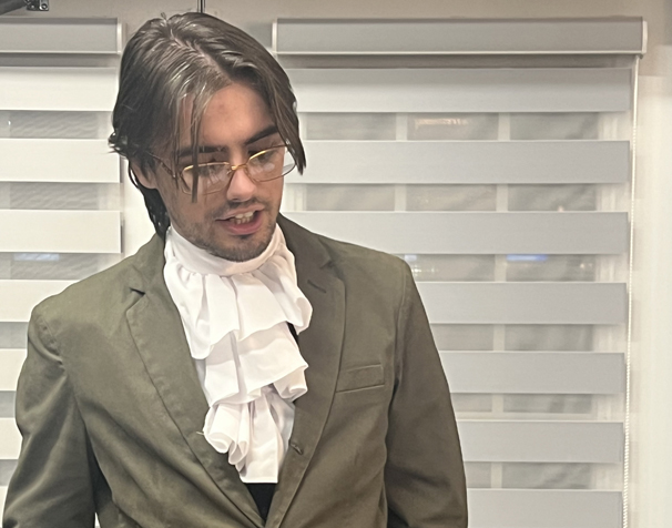a man standing and speaking dressed in 19 century formal clothing