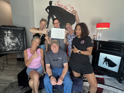 One man surrounded by 5 women pointing to him with a sign that says Thanks Craig Who invited you anyway